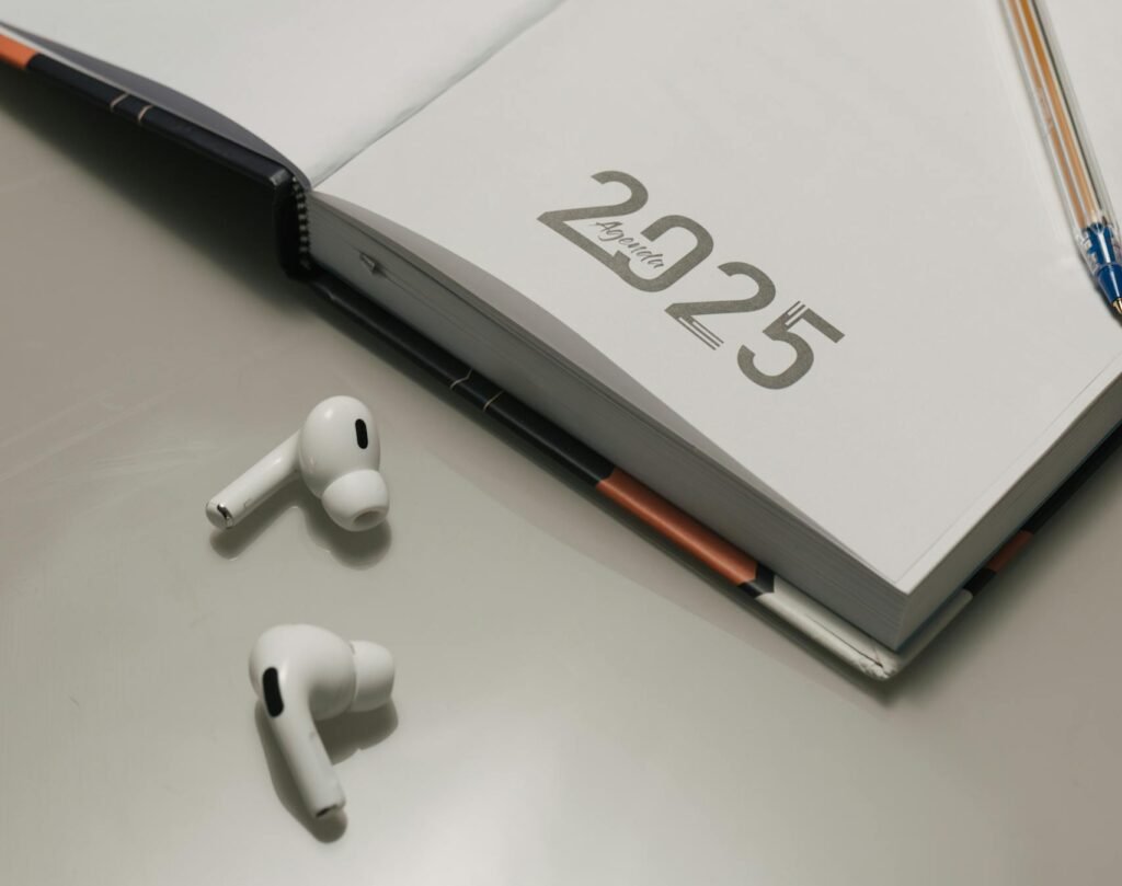 A tidy desk setup featuring a 2025 planner, sticky notes, and wireless earphones, ideal for organization.