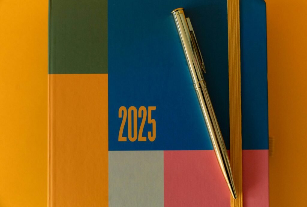 Modern 2025 planner with vibrant colors and a sleek silver pen on a flat lay design.