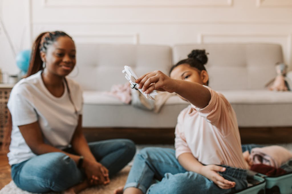 Mother and daughter playing with a toy airplane in a cozy living room.